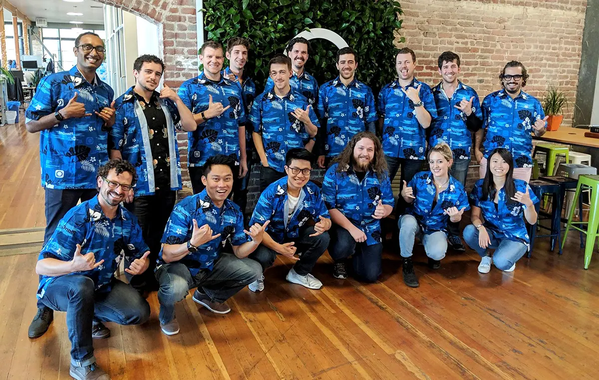 A tech team in matching blue Hawaiian shirts in their office